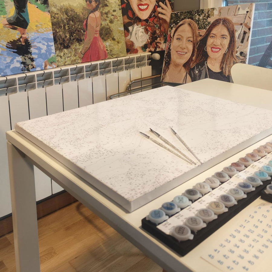 Kit personalizado sobre la mesa: lienzo con el diseño numerado, pinturas y pinceles